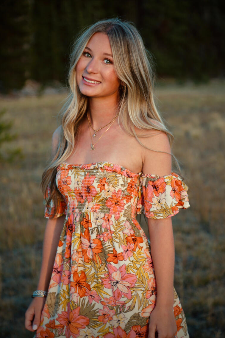 Outdoor editorial portrait of Jada wearing a coral floral dress in warm evening light.